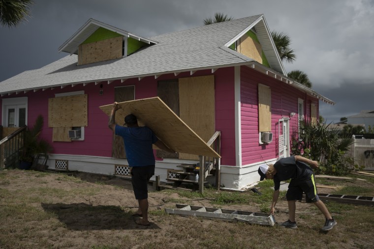 Zak Shaler (right) and Caleb Forney drill wooden boards over the windows of Caleb's mother's home in Flagler Beach, Fla., on Aug. 31, 2019. Though forecasters don't believe Hurricane Dorian will make landfall in Florida, many locals remain concerned storm surge could cause extensive damage in this small beachside community.